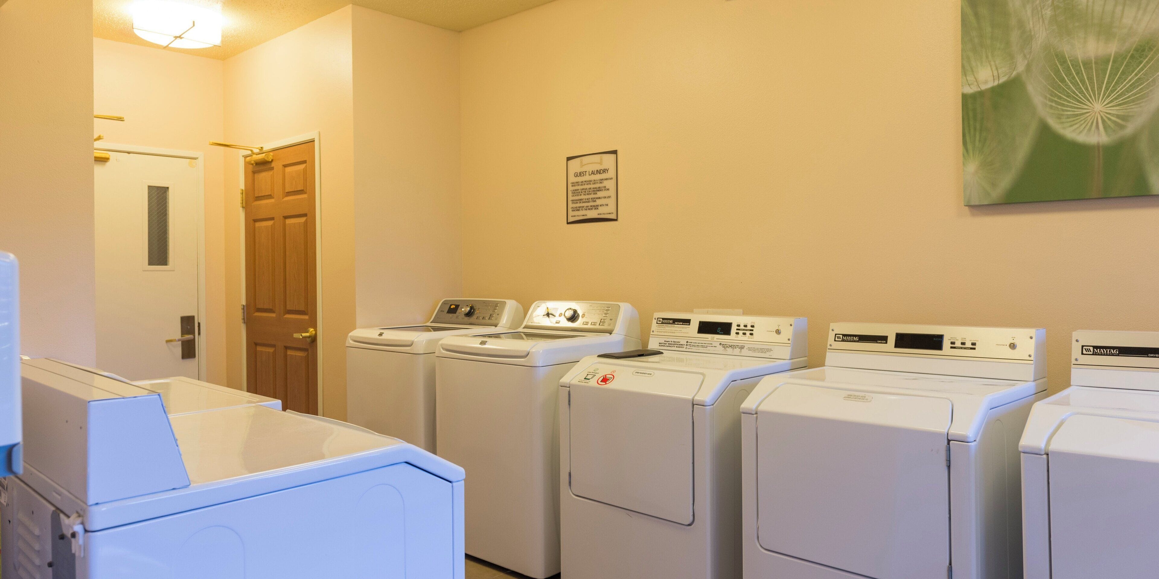 A laundry room with multiple washing machines and dryers, a door, and a wall-mounted sign.