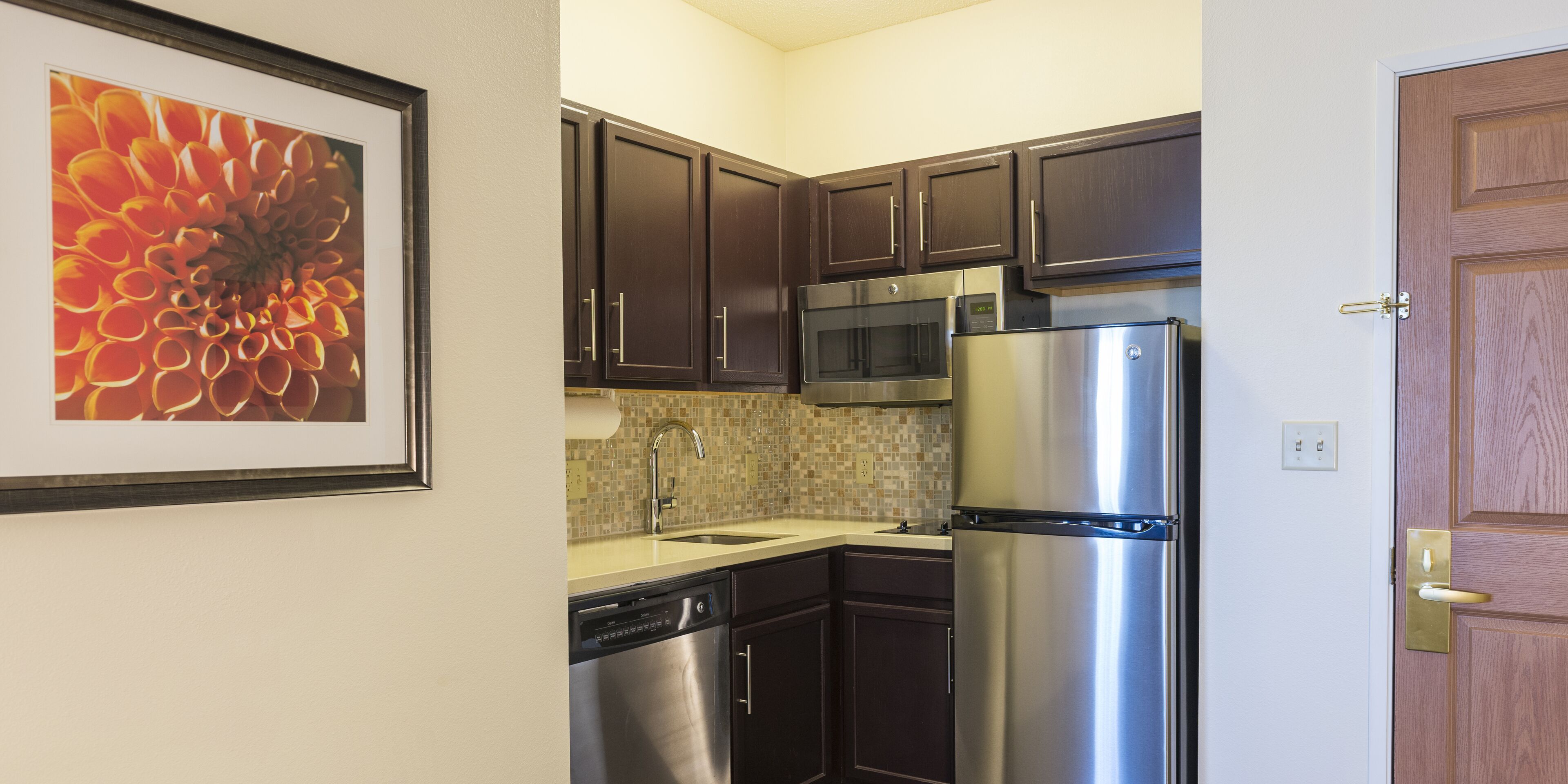 A kitchen with dark cabinets, stainless steel appliances, a dishwasher, and a microwave.