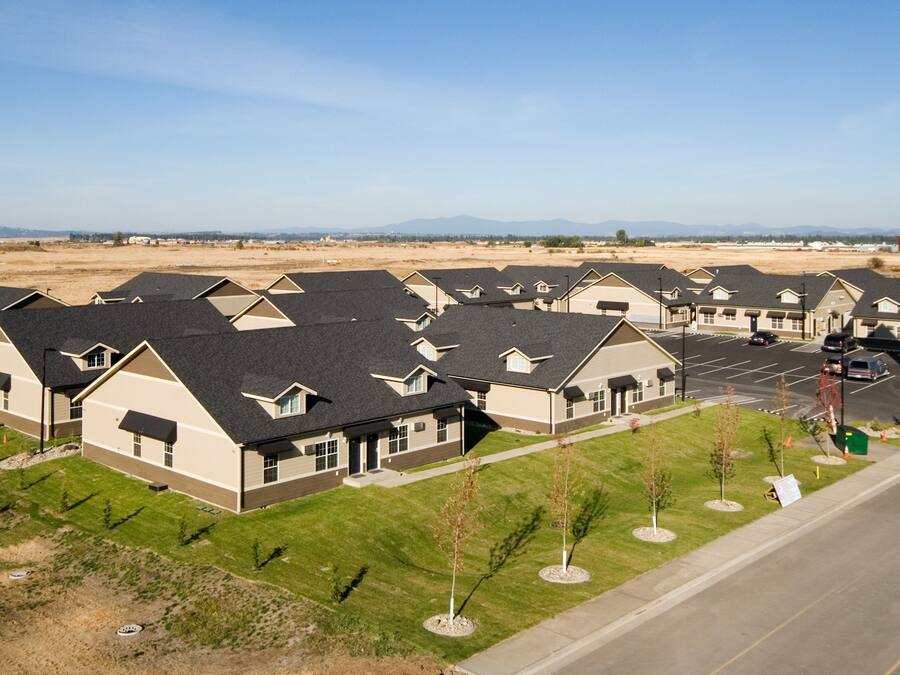 Fila de casas modernas de una sola planta con un estacionamiento al frente, identificadas como 'Stratford Suites Furnished'.
