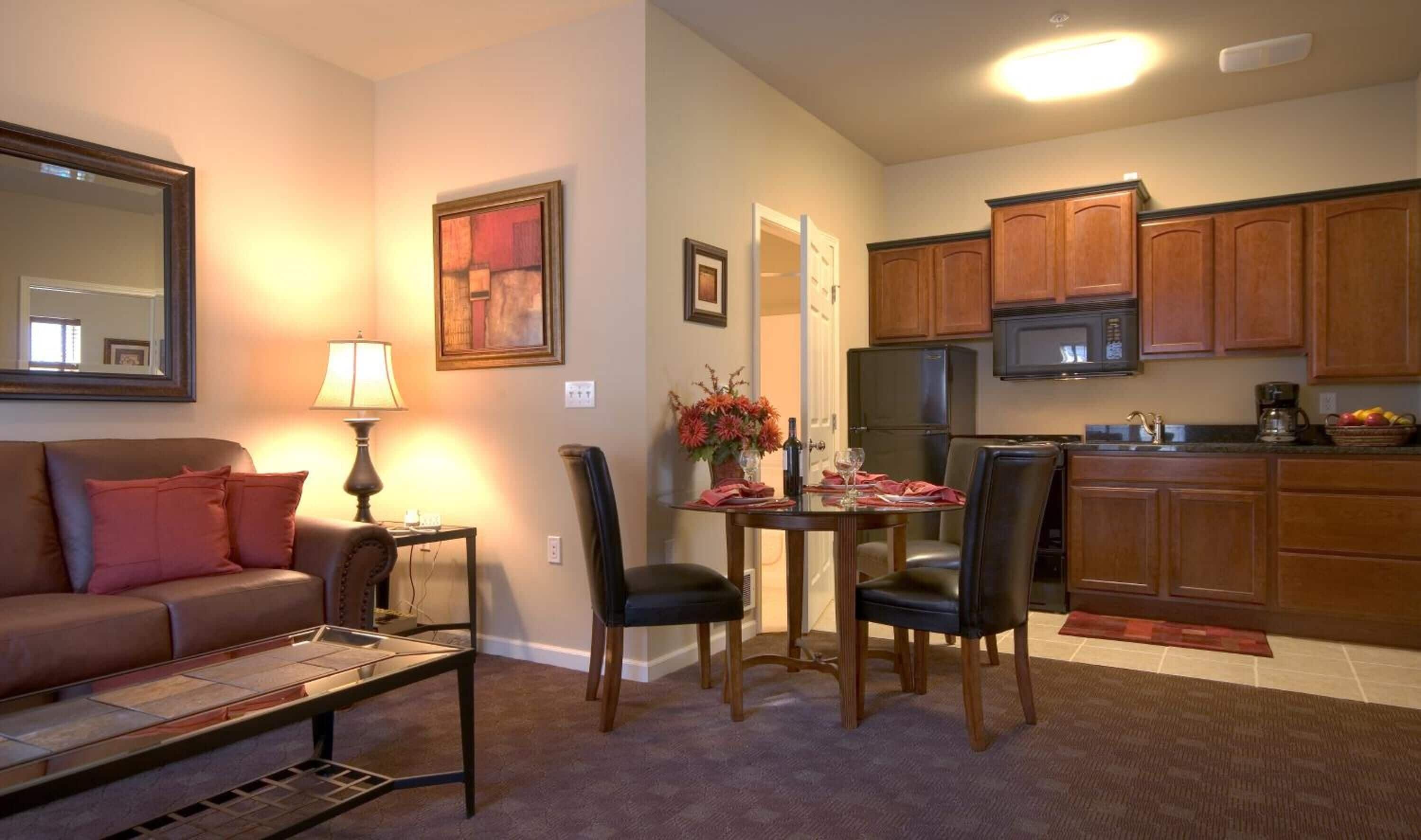 Una sala de estar con un sofá, una mesa baja y un comedor con sillas y una mesa dispuesta para dos personas.
