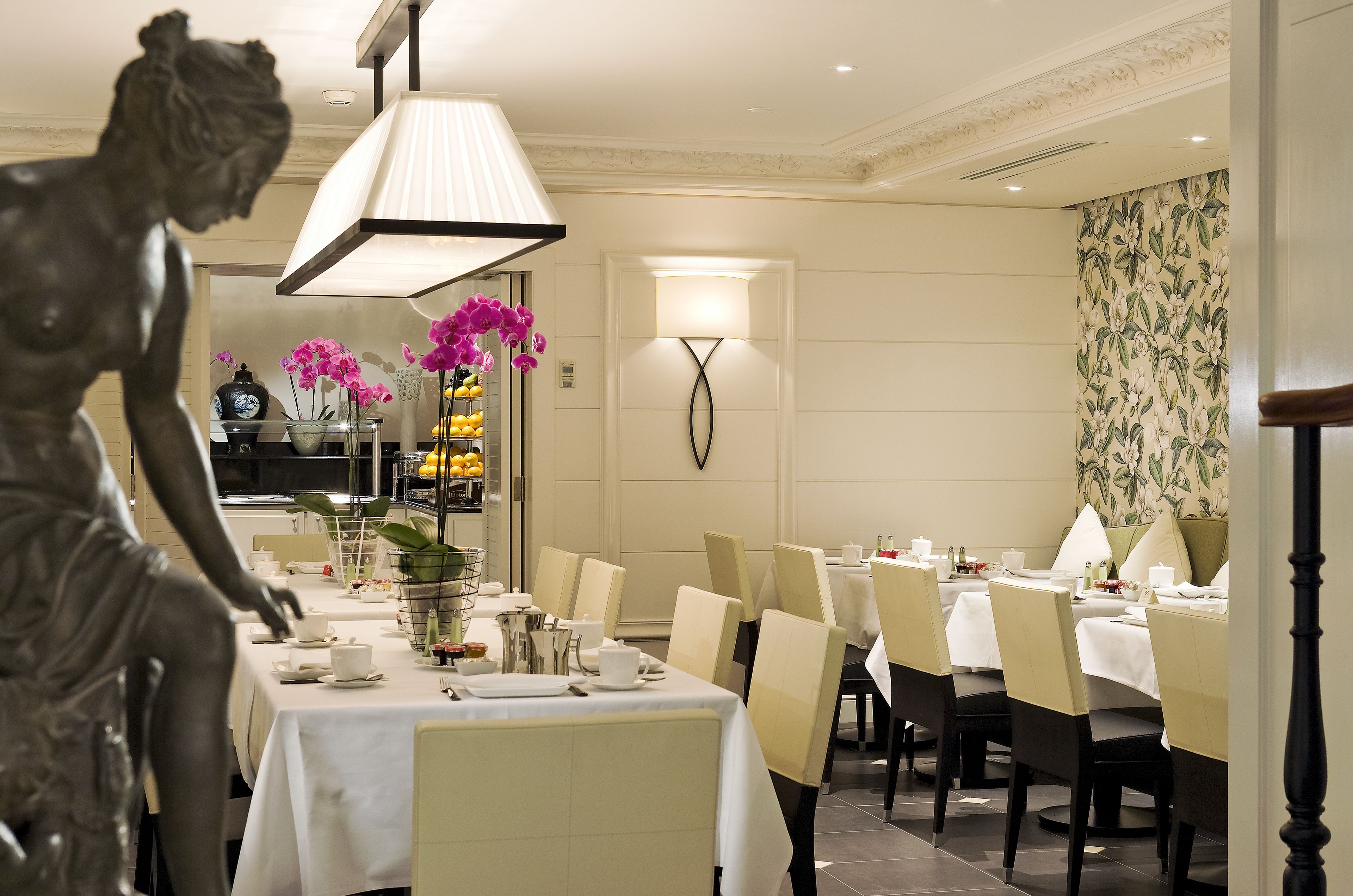 Un espace repas avec des tables dressées pour le repas, une statue et une lampe fixée au mur.