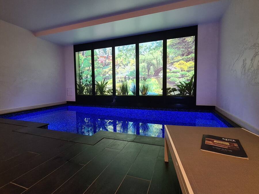 Una piscina interior moderna con vistas a un jardín a través de amplios ventanales.