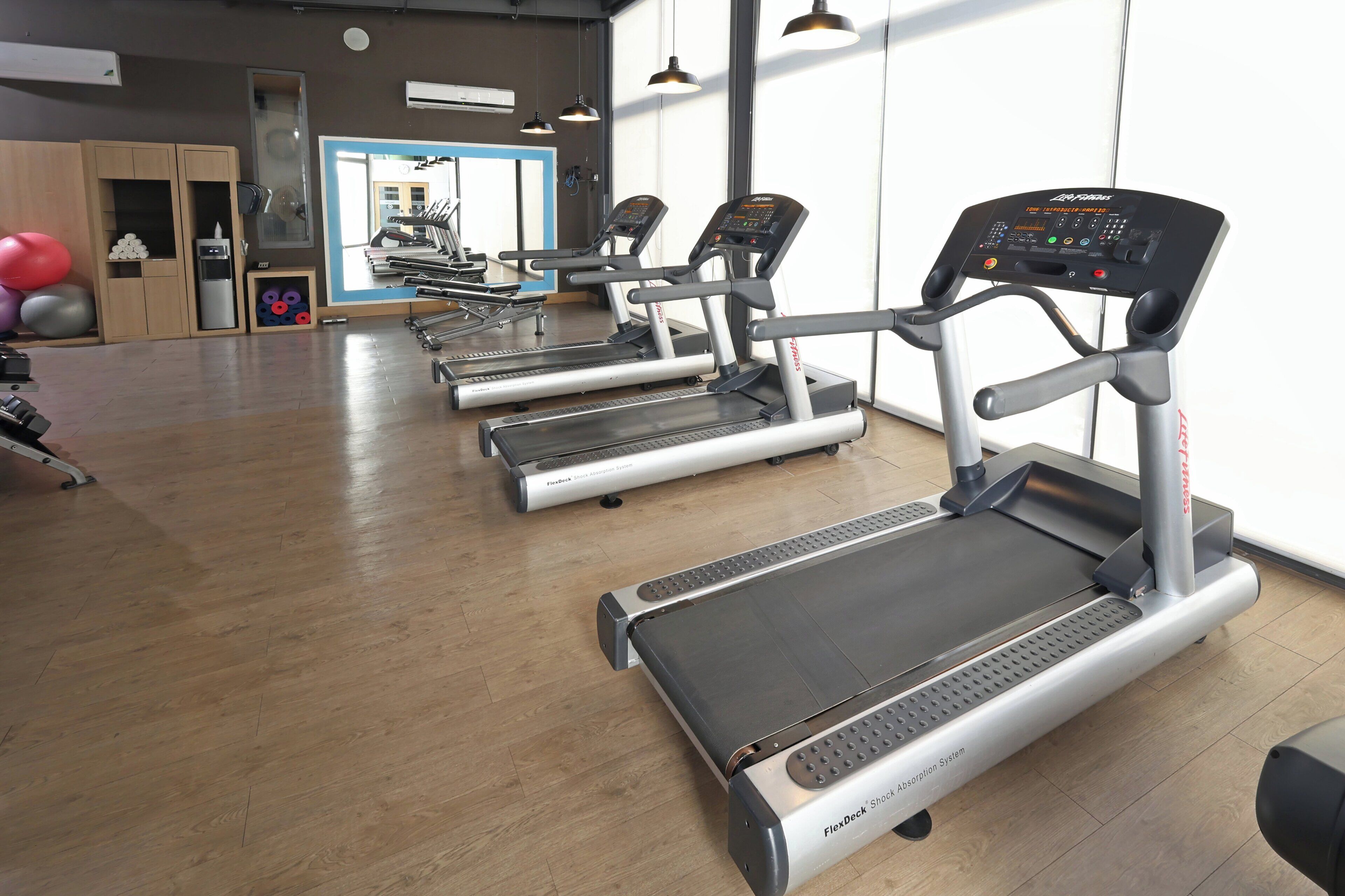 Un gimnasio con cintas de correr, pelotas de ejercicio y un espejo.