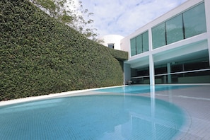 A modern building with a swimming pool, a hedge, and large windows. - Crowne Plaza Villahermosa by IHG (Villahermosa)