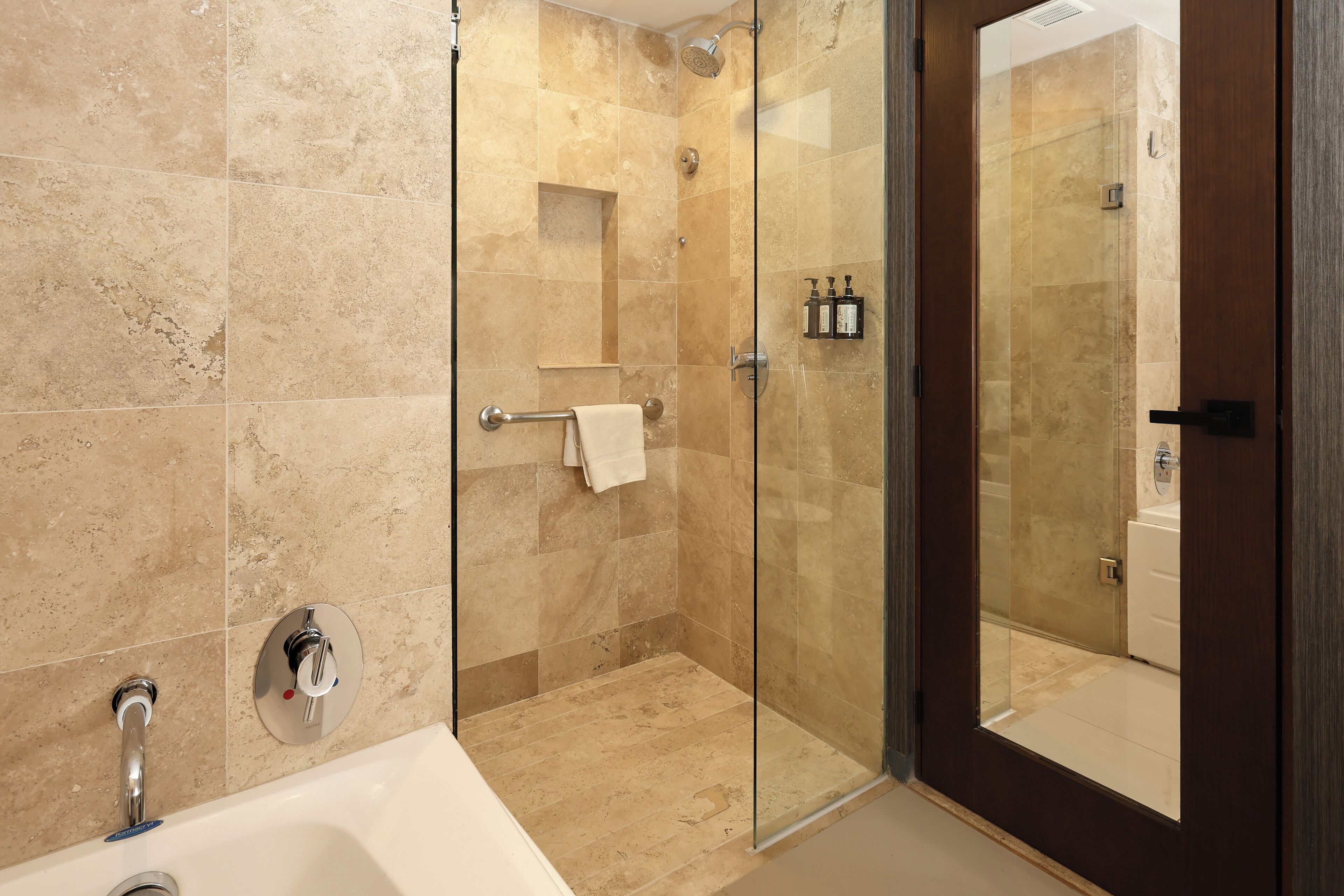 A modern bathroom with a glass-enclosed shower, a bathtub, and a toilet.