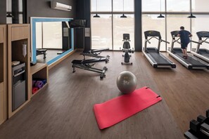 Un gimnasio con cintas de correr, bicicletas estáticas y una pelota grande para ejercicios.