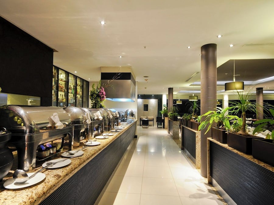 A buffet setup with multiple food stations, a seating area, and potted plants.