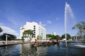 Un hotel con una fuente, una estatua y un cielo azul despejado.