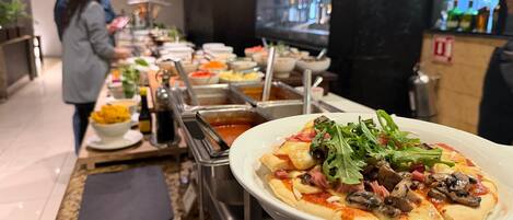 Un buffet proposant une variété de plats, avec une pizza au premier plan.