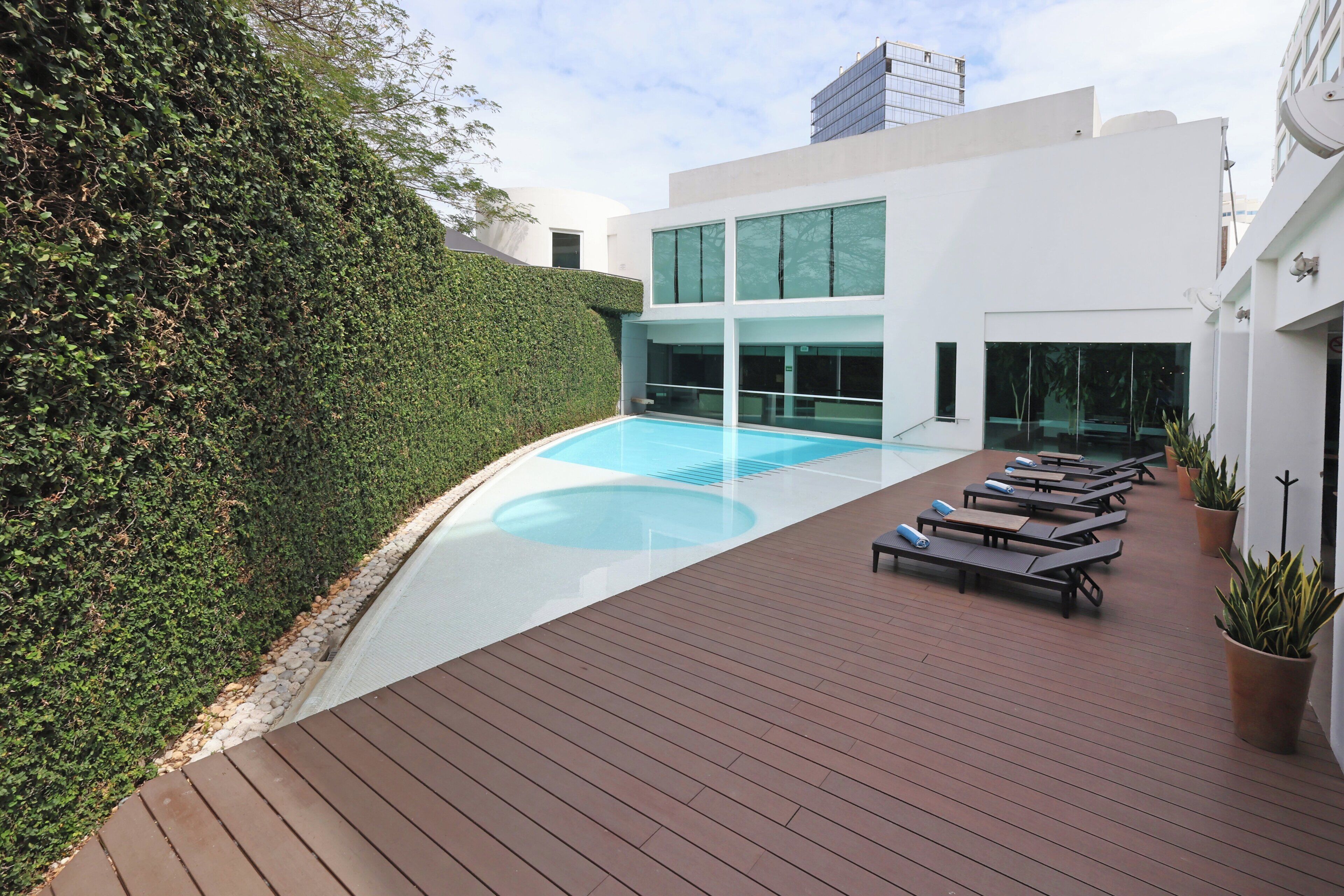 A modern outdoor pool area with lounge chairs and a wooden deck.