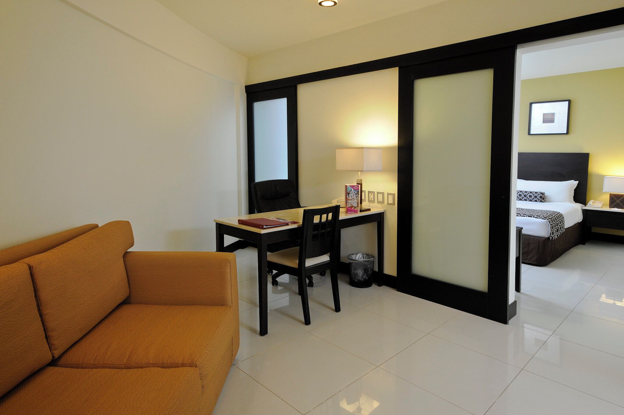 Una habitación de hotel con sofá, escritorio, cama y mesita de noche.