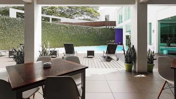 An outdoor patio area with a wooden table and chairs, a pool, and potted plants. - Crowne Plaza Villahermosa by IHG (Villahermosa)