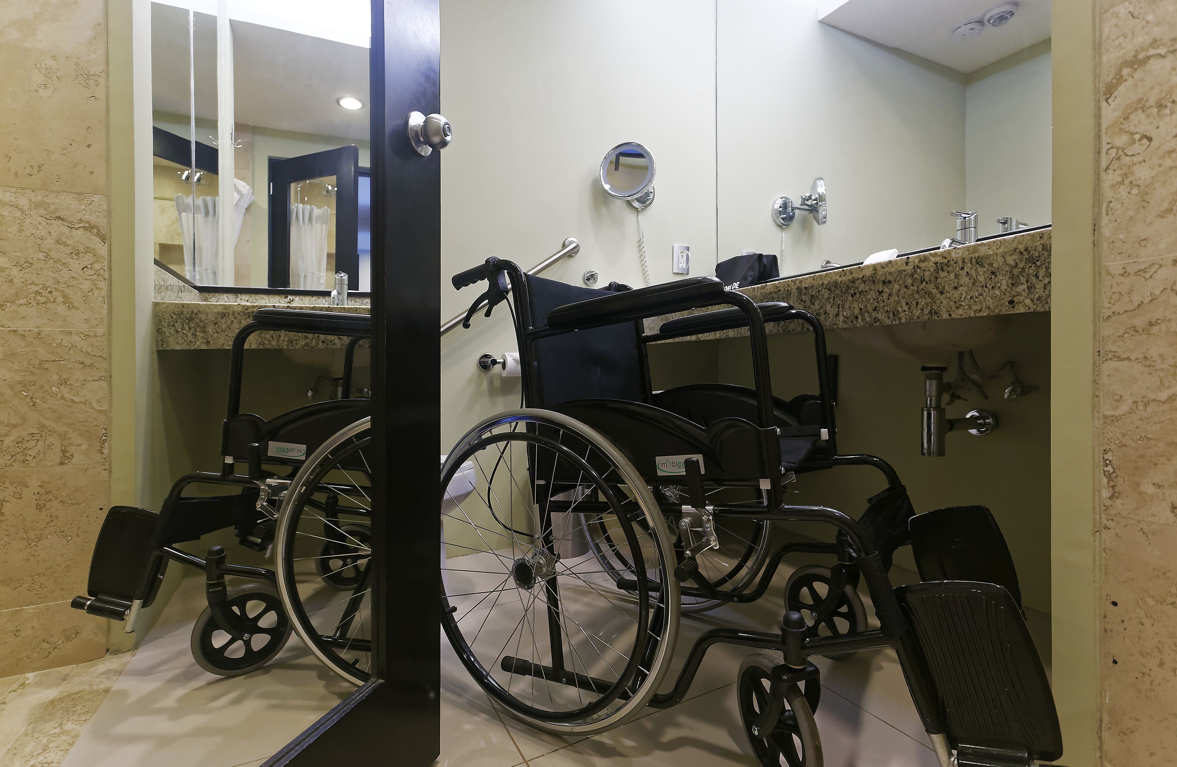 Un baño con dos sillas de ruedas, un lavamanos y un espejo.