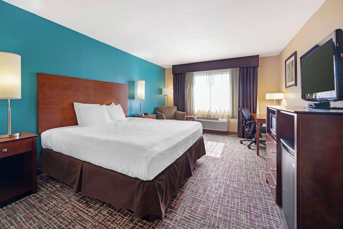 A hotel room with a large bed, a desk with a computer, a TV, and a chair.