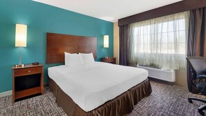 Habitación de hotel con una cama grande, dos mesitas de noche, un escritorio con silla, una ventana con cortinas y un calentador de pared.