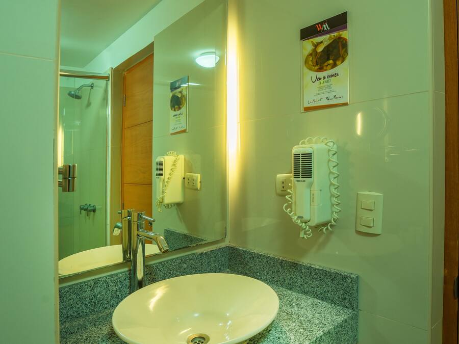 Une salle de bain équipée d’un lavabo, d’un miroir, d’un sèche-cheveux et d’articles de toilette.