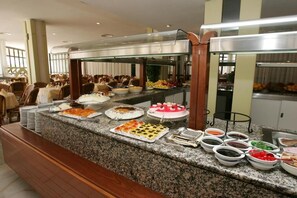 Zona de bufé con diversos alimentos y platos presentados sobre una encimera de granito.