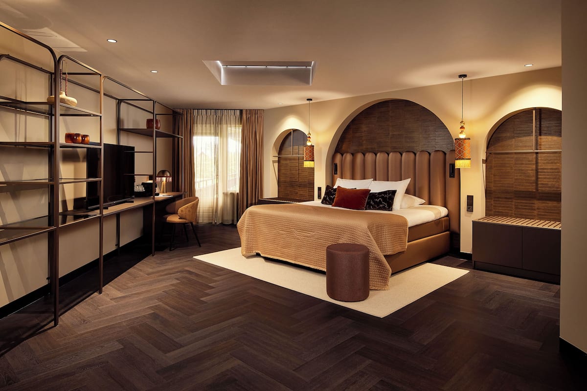 A modern bedroom with a large bed, a desk, and shelving units.