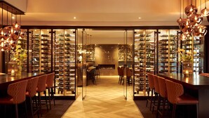 Una zona de bar con una estantería para vinos y asientos.