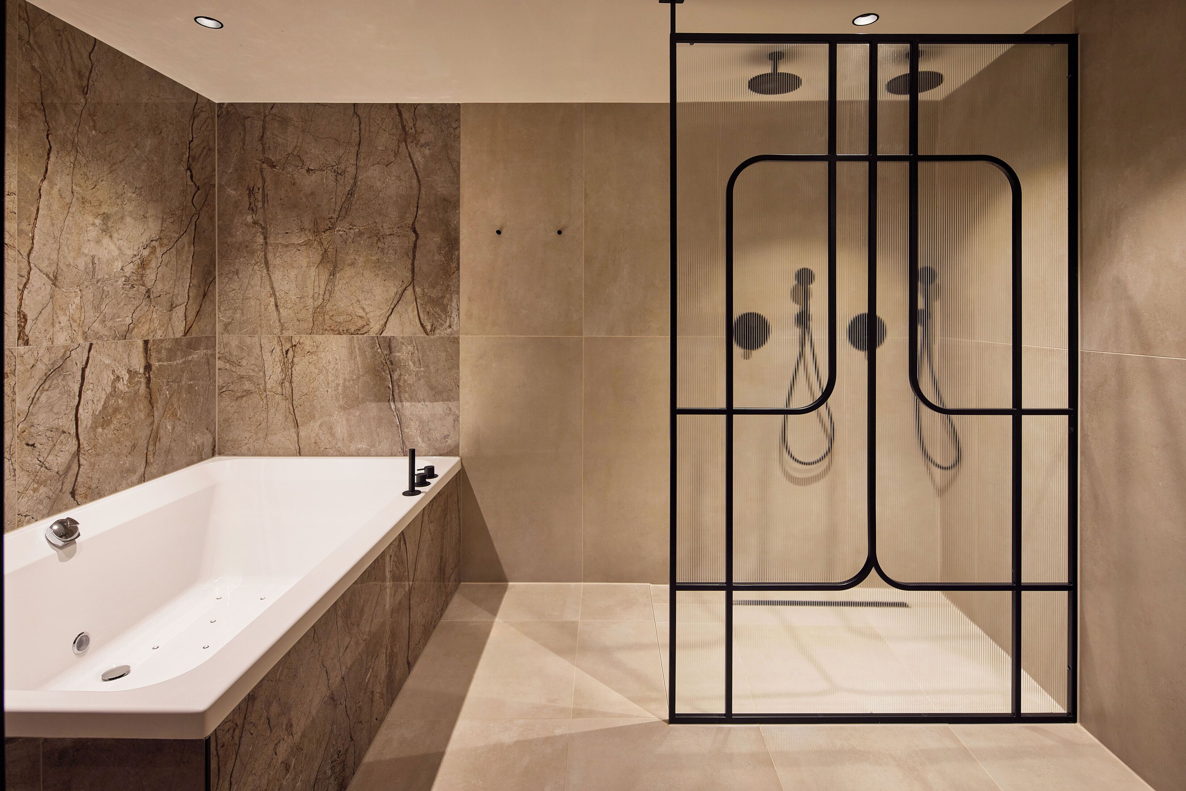 Ein modernes Badezimmer mit freistehender Badewanne, einer gläsernen Dusche und Marmorwänden.