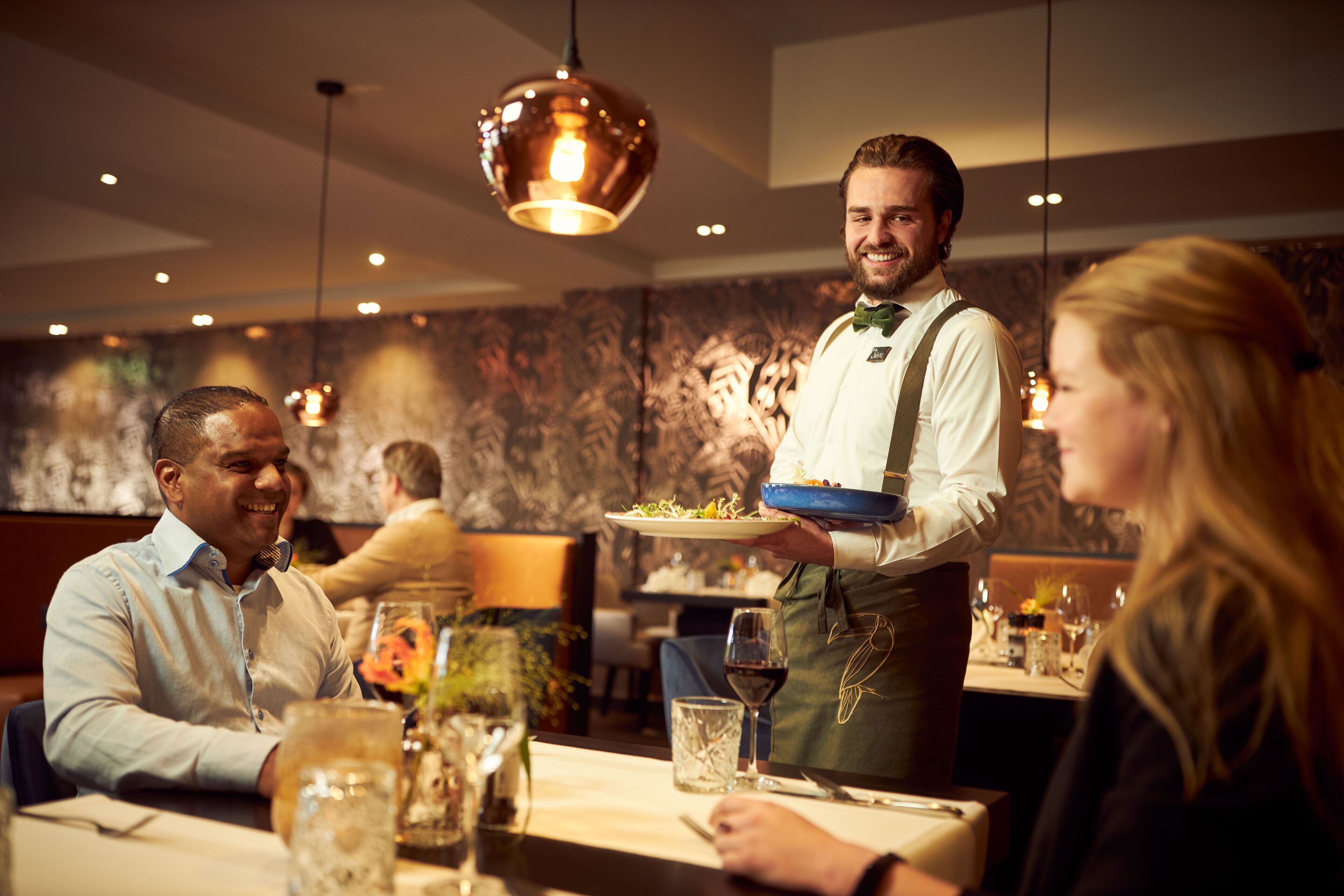 L'intérieur d'un restaurant, avec des tables, des chaises et des lampes suspendues.