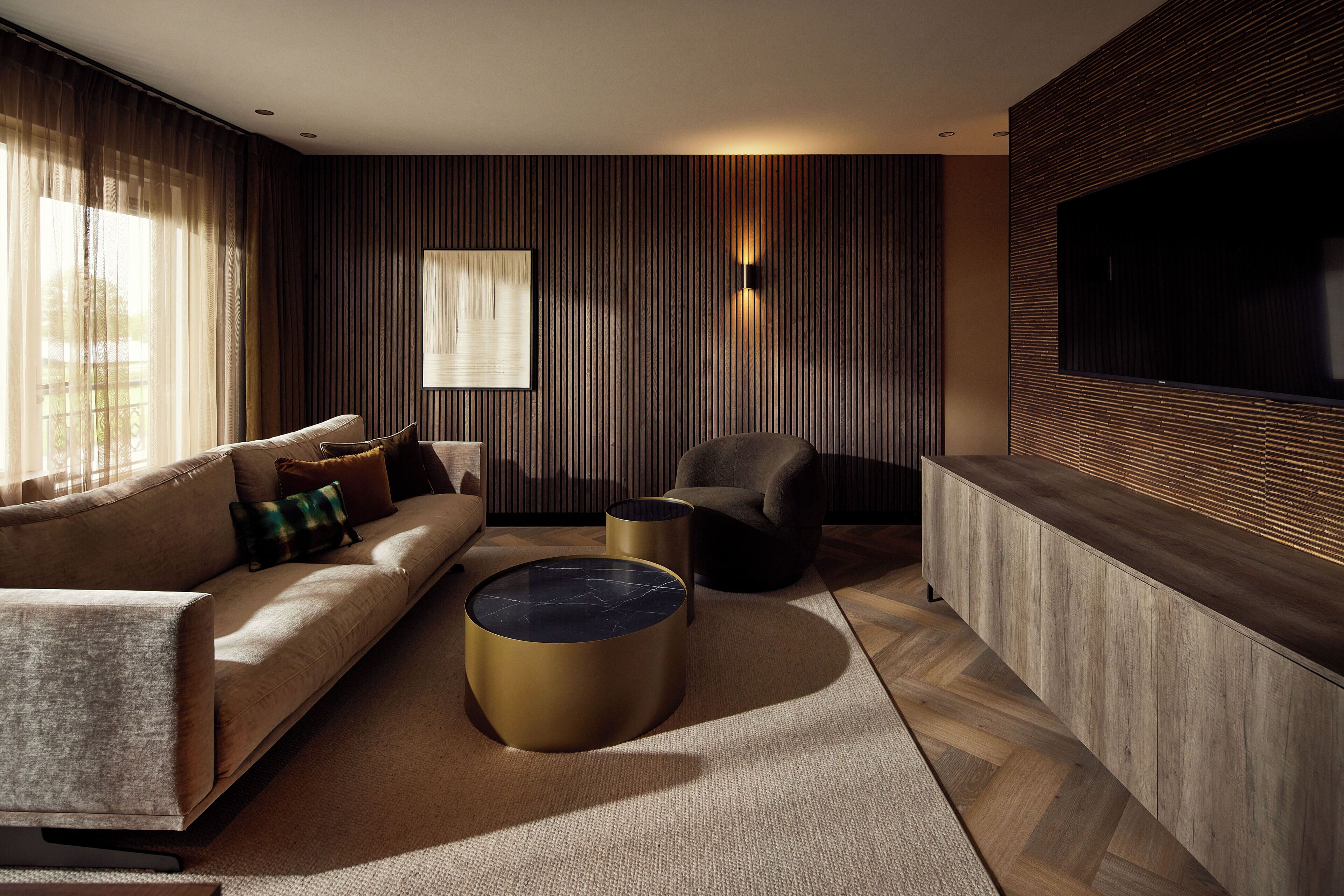 A modern living room with a sofa, two round coffee tables, a chair, and a TV mounted on the wall.