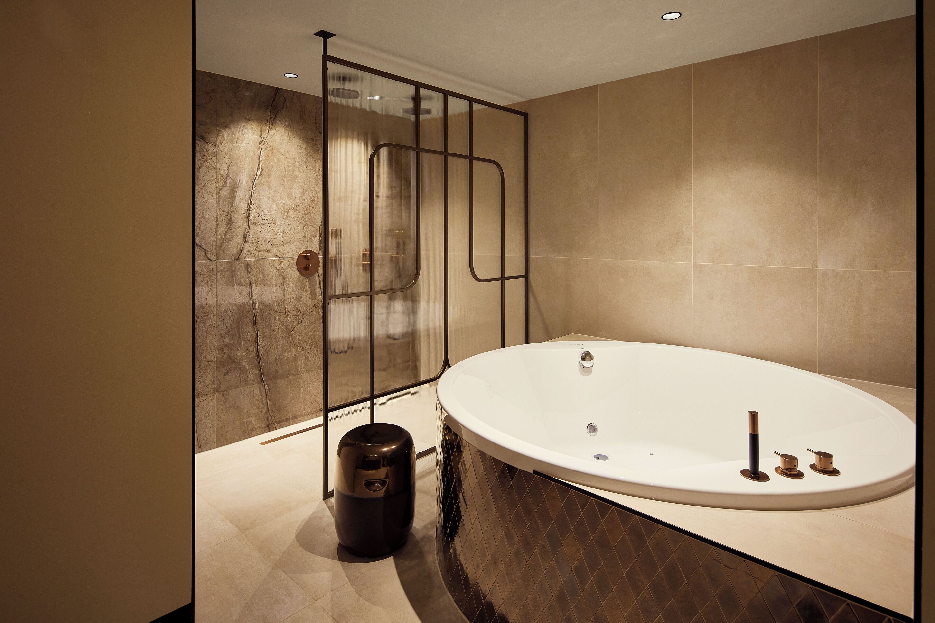 A modern bathroom with a freestanding bathtub, a glass shower enclosure, and a marble-tiled floor.