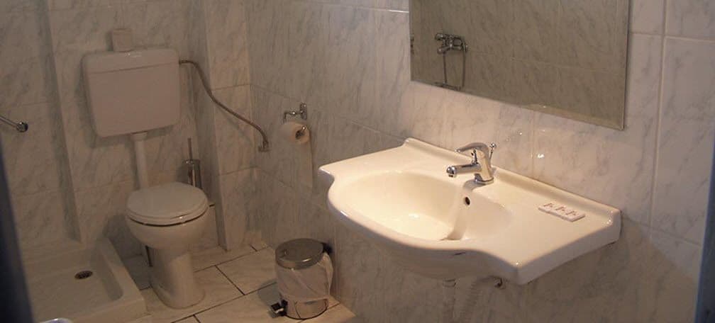 A bathroom with a toilet, sink, and mirror.