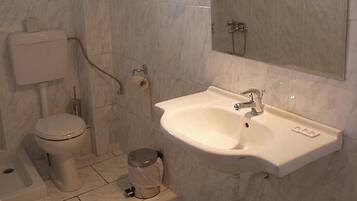 A bathroom with a toilet, sink, and mirror.