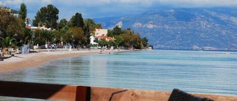 A coastal view with a beach, a mountain in the background, and a chair with a drink.