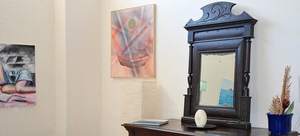 A room with a dark wooden cabinet, a white spherical object on top, and a blue vase with dried plants.