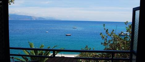 A balcony with a view of the ocean, featuring a table and chairs.