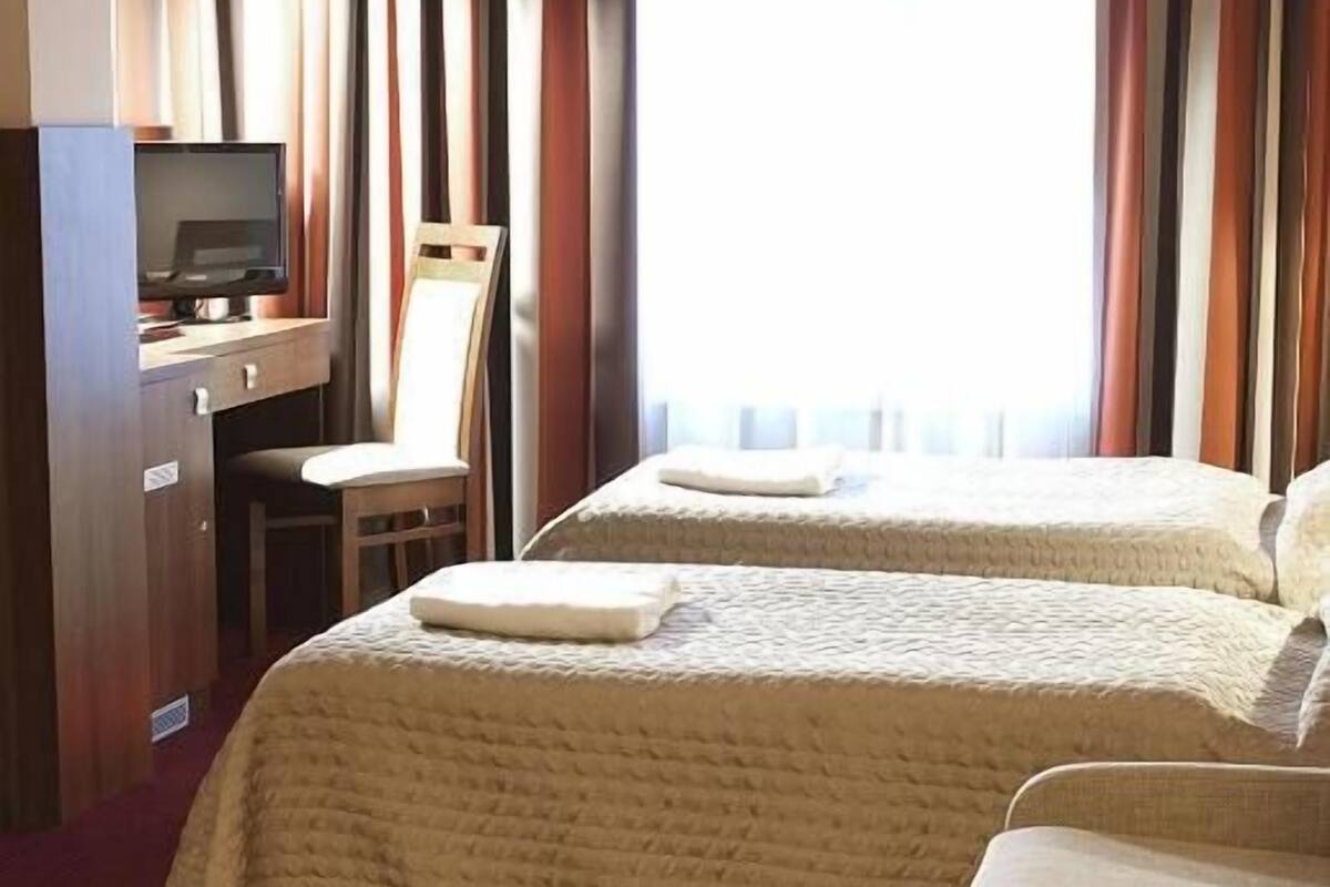 Habitación de hotel con dos camas, un escritorio con silla y un televisor.