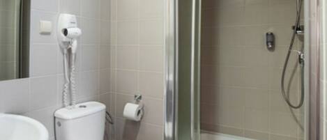 Un baño con inodoro, lavabo, ducha y cabina de ducha con mampara de vidrio.
