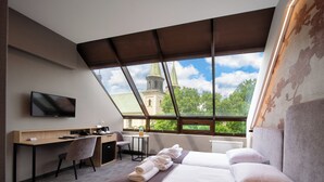 Une chambre d’hôtel avec une grande fenêtre, un bureau, un lit et une télévision.