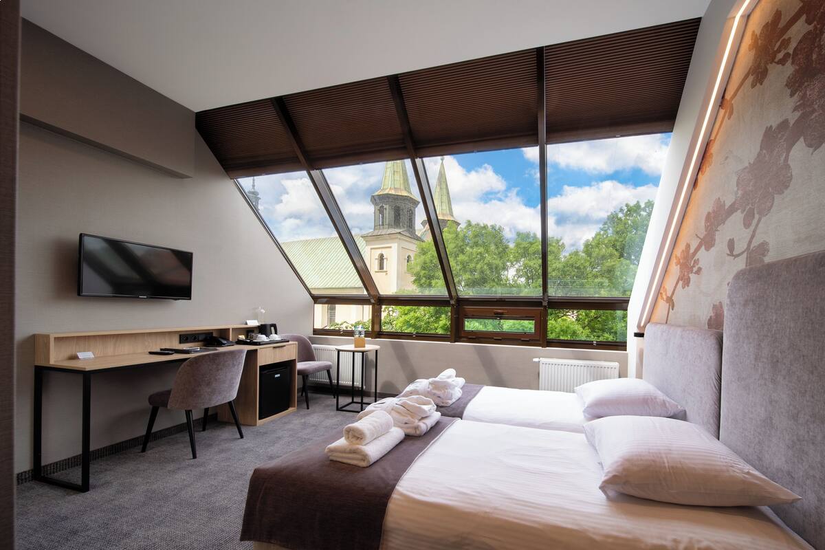 Una habitación de hotel con un ventanal grande, un escritorio, una cama y un televisor.