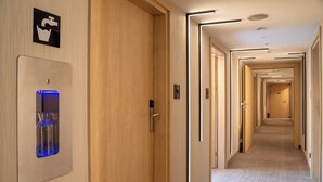 Un couloir d’hôtel avec des portes en bois, un distributeur d’eau et un extincteur.