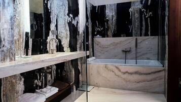Un baño moderno con tocador de mármol, bañera y un espejo grande.