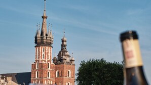 A table with wine glasses and a bottle, set against a backdrop of a historic building with multiple spires. - Hotel Stary (Kraków)