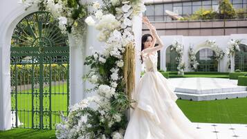 A wedding venue with a green gate, white floral decorations, and a white dress.