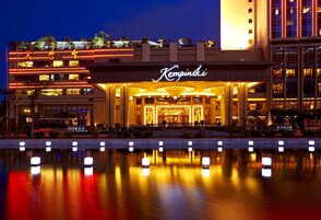 A hotel with a prominent entrance, a reflective pool in front, and a well-lit facade.