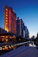 A hotel with a prominent sign, a reflection pool, and modern architecture.