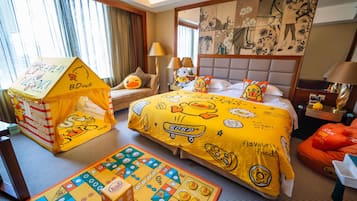 A hotel room with a bed, a playhouse, a board game, and a pillow with duck designs.