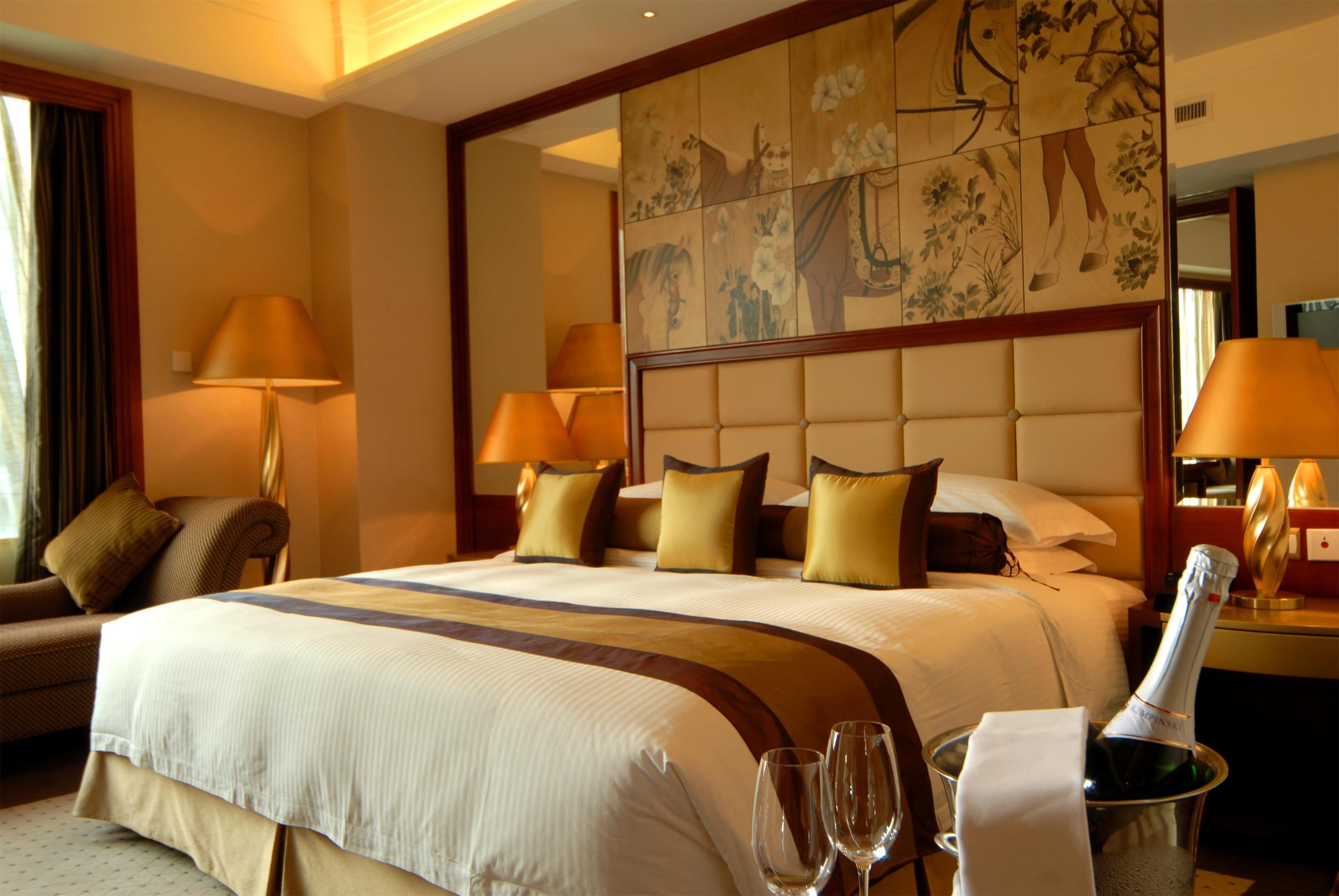 Une chambre d’hôtel avec un grand lit, deux tables de chevet, une chaise, un mur décoratif et un mini-bar.