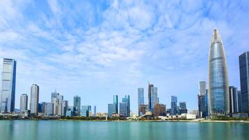 A city skyline with modern skyscrapers, a body of water in the foreground, and a clear sky.