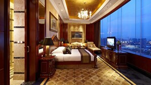 Ein luxuriöses Hotelzimmer mit einem großen Bett, einem Fernseher und Blick auf die Stadtlandschaft.