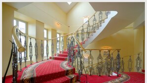 A grand staircase with ornate metal railings and red carpeted steps.