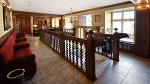 A spacious lobby with a red sofa, wooden staircase, and a chandelier.