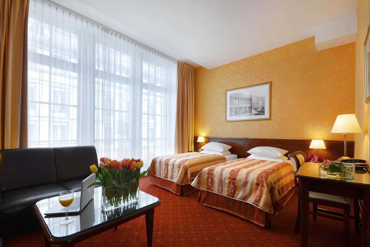A hotel room with two beds, a sofa, a desk, and a laptop.