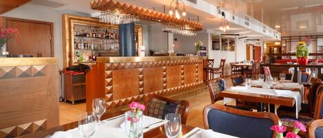 A restaurant with a bar area, wooden furniture, and a modern interior design.